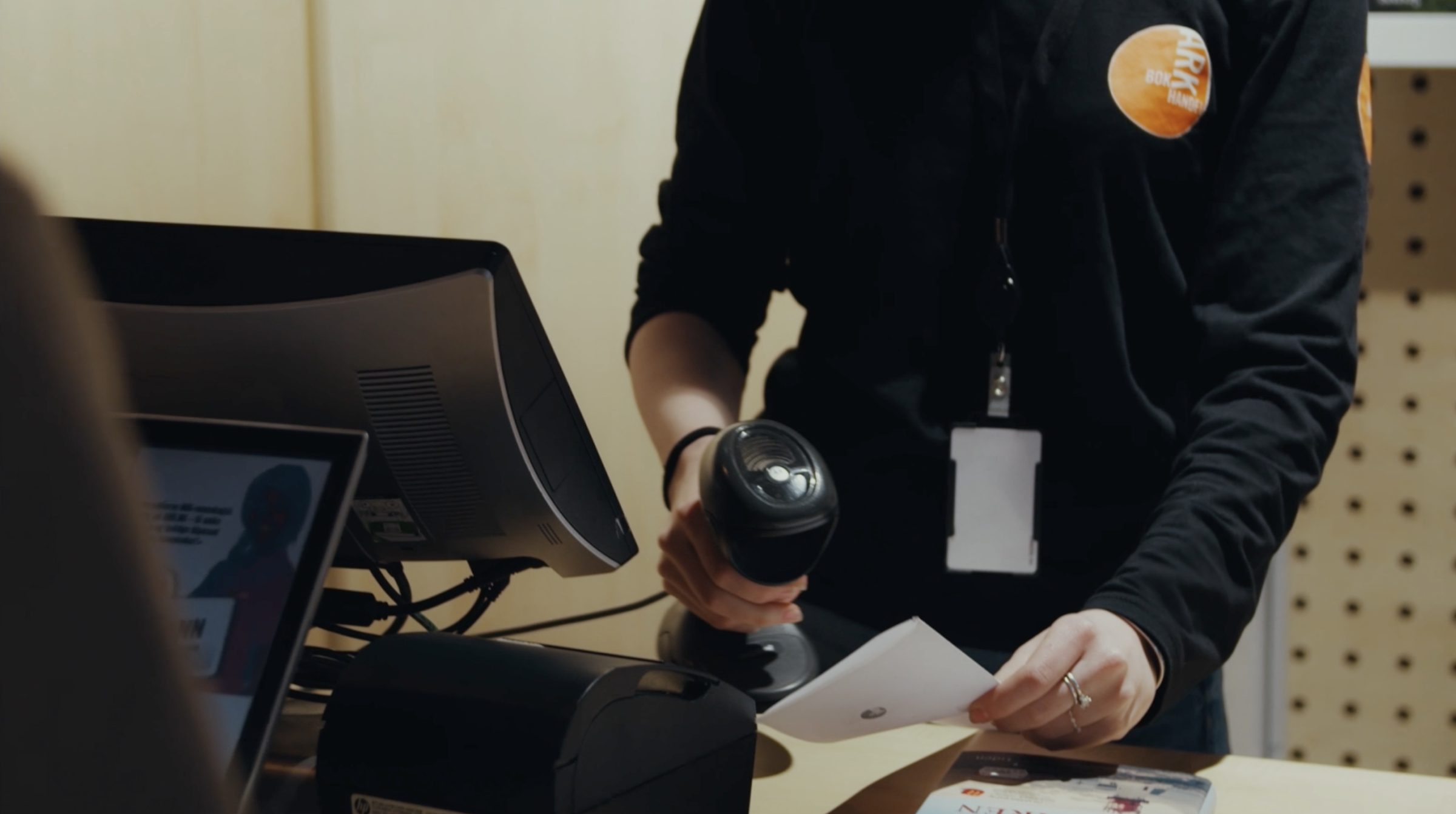 ARK store employee scanning a product at the checkout counter.